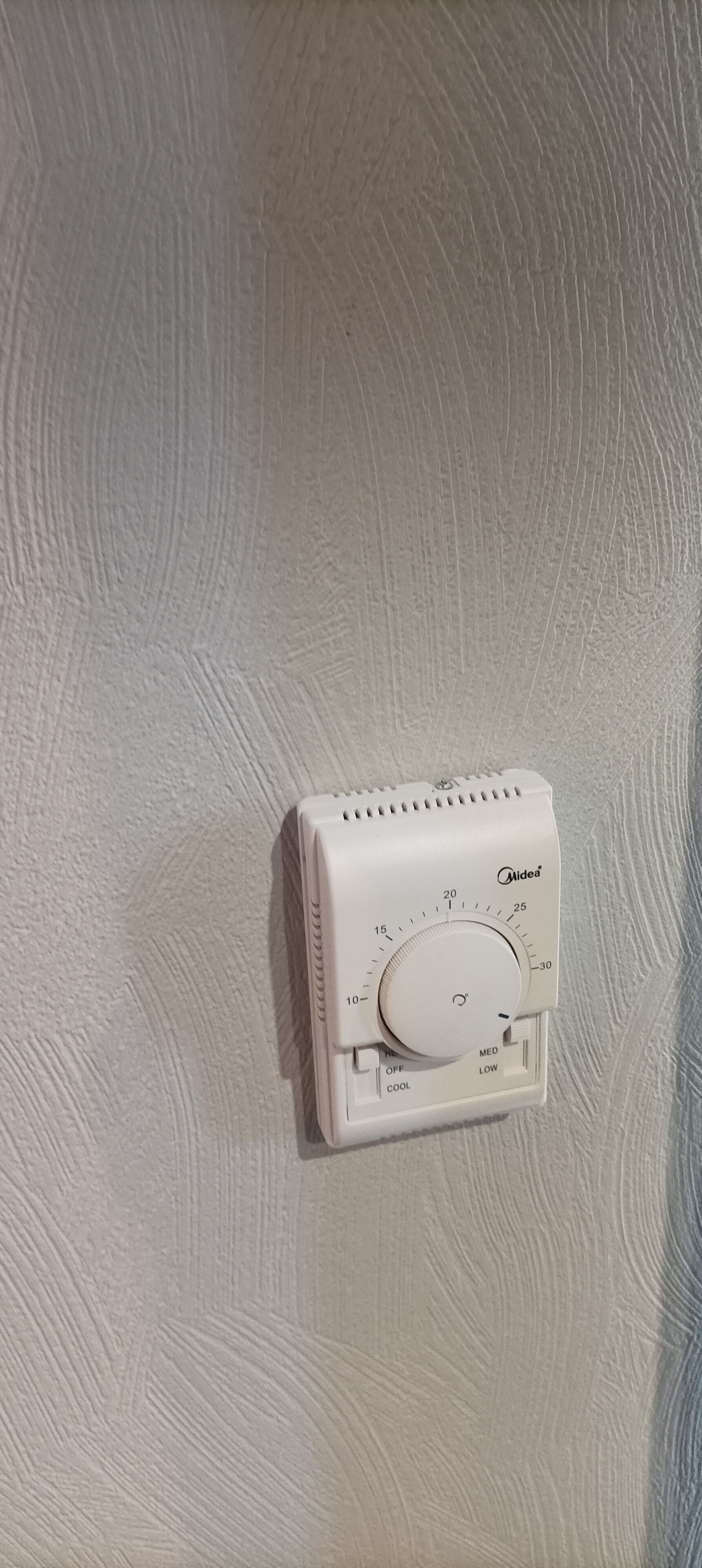 Een thermostaat aan een structuurrijke muur.