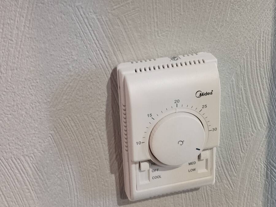 Een thermostaat aan een structuurrijke muur.