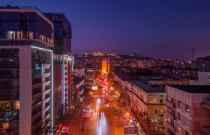A cityscape at dusk with illuminated buildings and a prominent tower. -  Onyx City Center (Tbilisi)