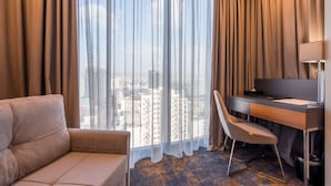 A hotel room with a large window, a sofa, a desk with a chair, and a TV. -  Onyx City Center (Tbilisi)