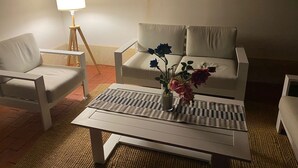 Ett vardagsrum med en soffa, en fåtölj och ett soffbord med en vas med blommor.