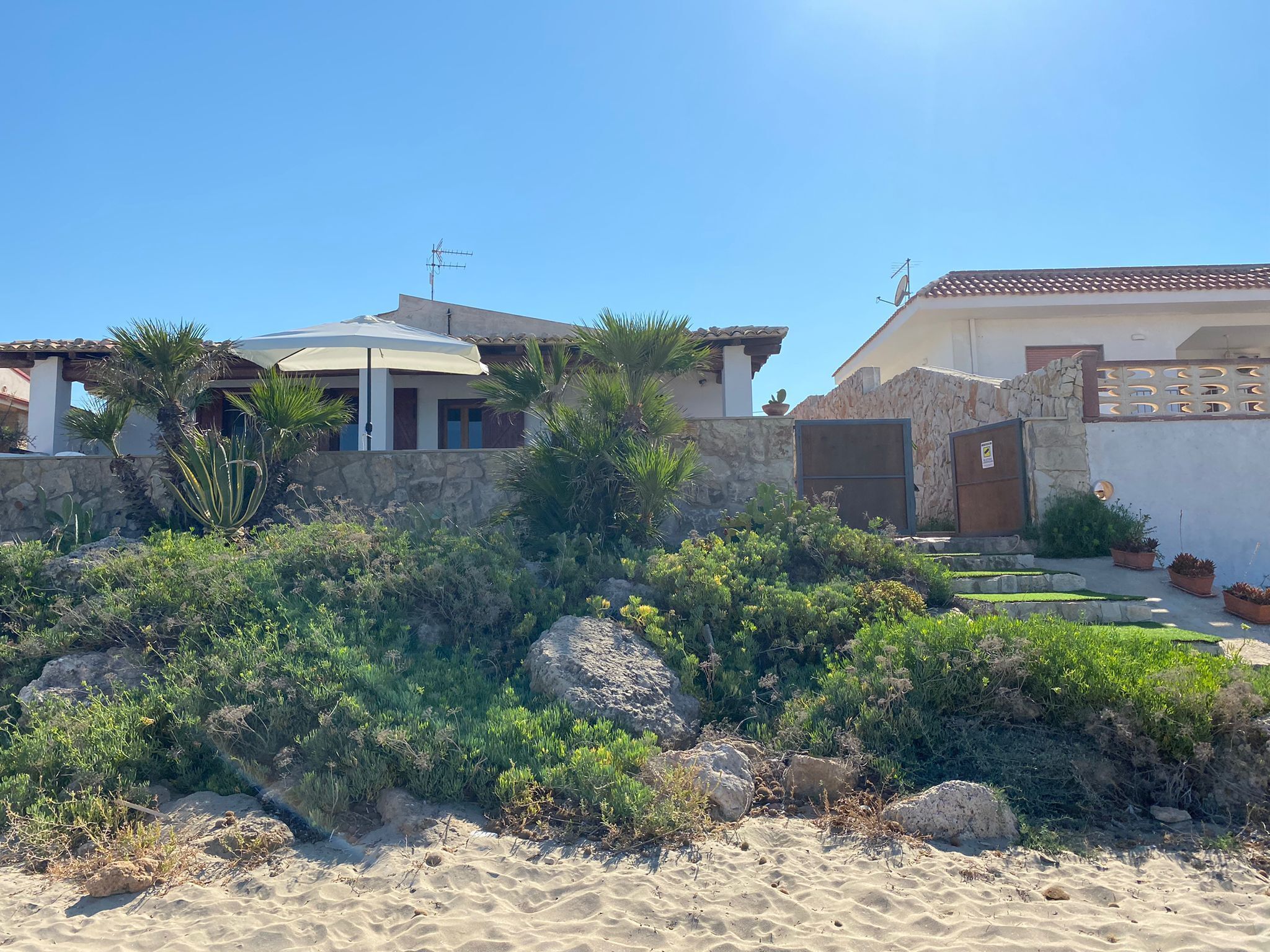 Ein Küstenanwesen mit Mauerwerk, einer überdachten Terrasse und Blick auf das Meer.