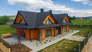 A modern house with a sloped roof, large windows, and a well-maintained lawn. - Apartamenty Sun & Snow Kaniówka (Bukowina Tatrzanska)