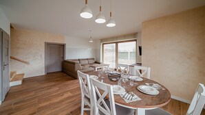 A dining area with a round wooden table set for four, surrounded by white chairs. - Apartamenty Sun & Snow Kaniówka (Bukowina Tatrzanska)