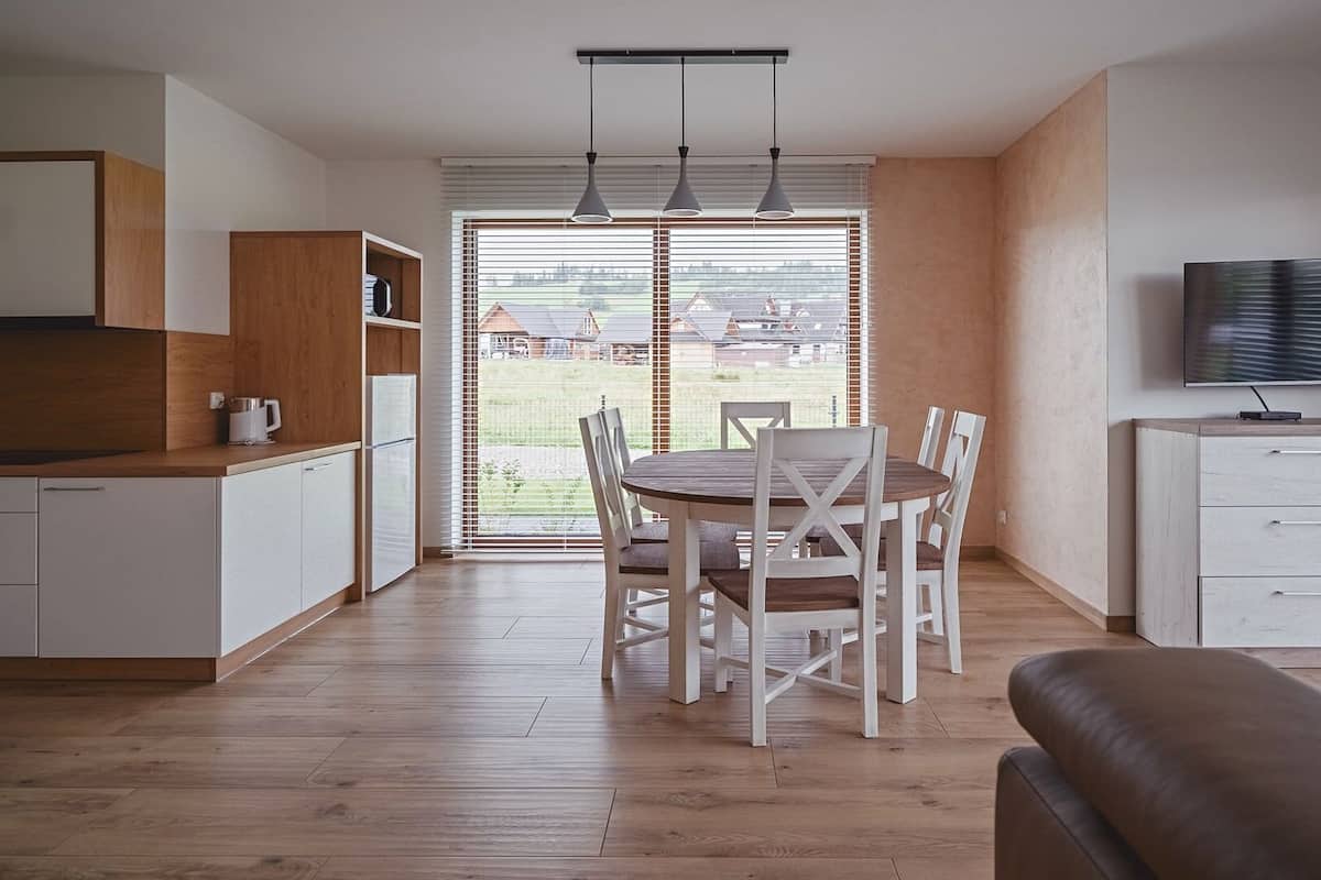 A modern kitchen with a dining area, a TV, and a view of the outdoors.