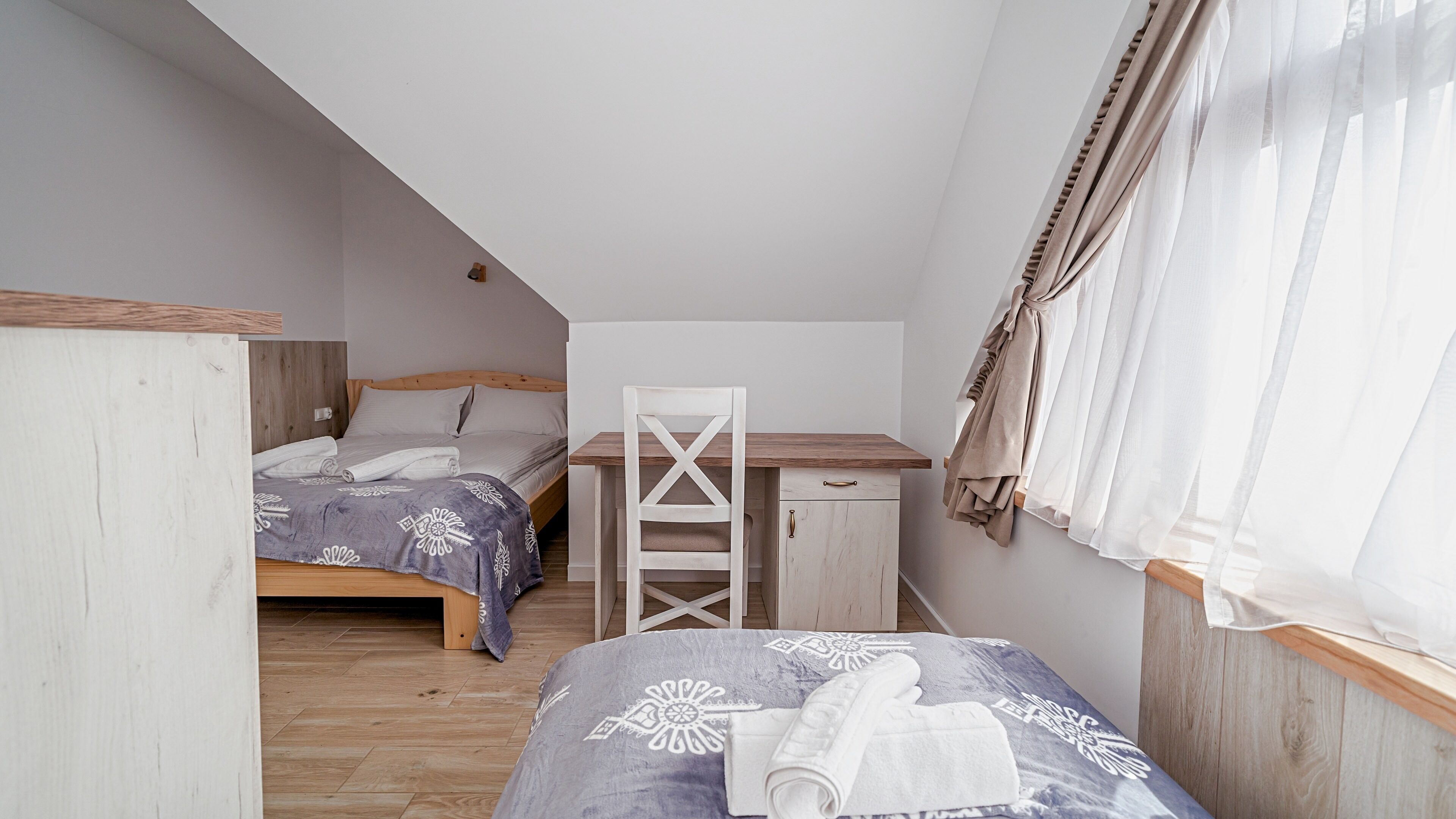 A bedroom with two beds, a desk, and a chair.