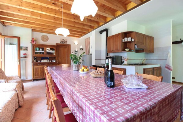 Una cocina acogedora con armarios de madera, una mesa de comedor con mantel a cuadros y una botella de vino.