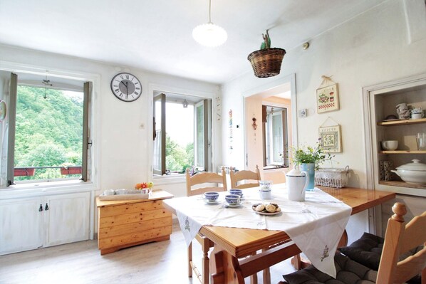 A cozy kitchen with wooden cabinets, a dining table set with blue and white dishes, and a hanging basket.