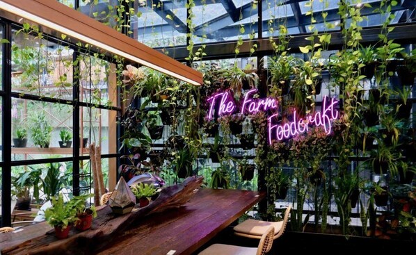 A greenhouse interior with hanging plants and a neon sign reading "The Farm Foodcraft." - Exclusive City Retreat | Rooftop Pool & King Comfort (Kuala Lumpur)