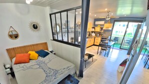 Un dormitorio con cama, mesita de noche y vistas a la cocina y el comedor.