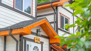 Un immeuble à plusieurs étages, doté d’un toit à pignon, d’un revêtement en bois et d’une entrée bien visible, avec une porte et une fenêtre.