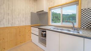 Une cuisine avec un dosseret à carreaux, une fenêtre donnant sur la verdure et un évier en acier inoxydable.