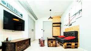 A modern living room with a flat-screen TV, a wooden cabinet, a sofa with red cushions, and a hanging light fixture. - INDUSTRIAL#CENTER#STATION#WIFI@SLEEPNTRIPBEZIERS (Béziers)