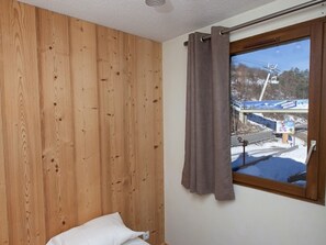 Enjoy a serene view of the snowy landscape from the comfort of this cozy room, featuring a single bed and a window with a ski lift in sight.