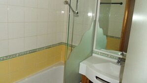 Un baño con bañera, cabina de ducha de vidrio y lavamanos con espejo.
