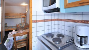 A compact kitchen with a stove, microwave, and coffee maker.