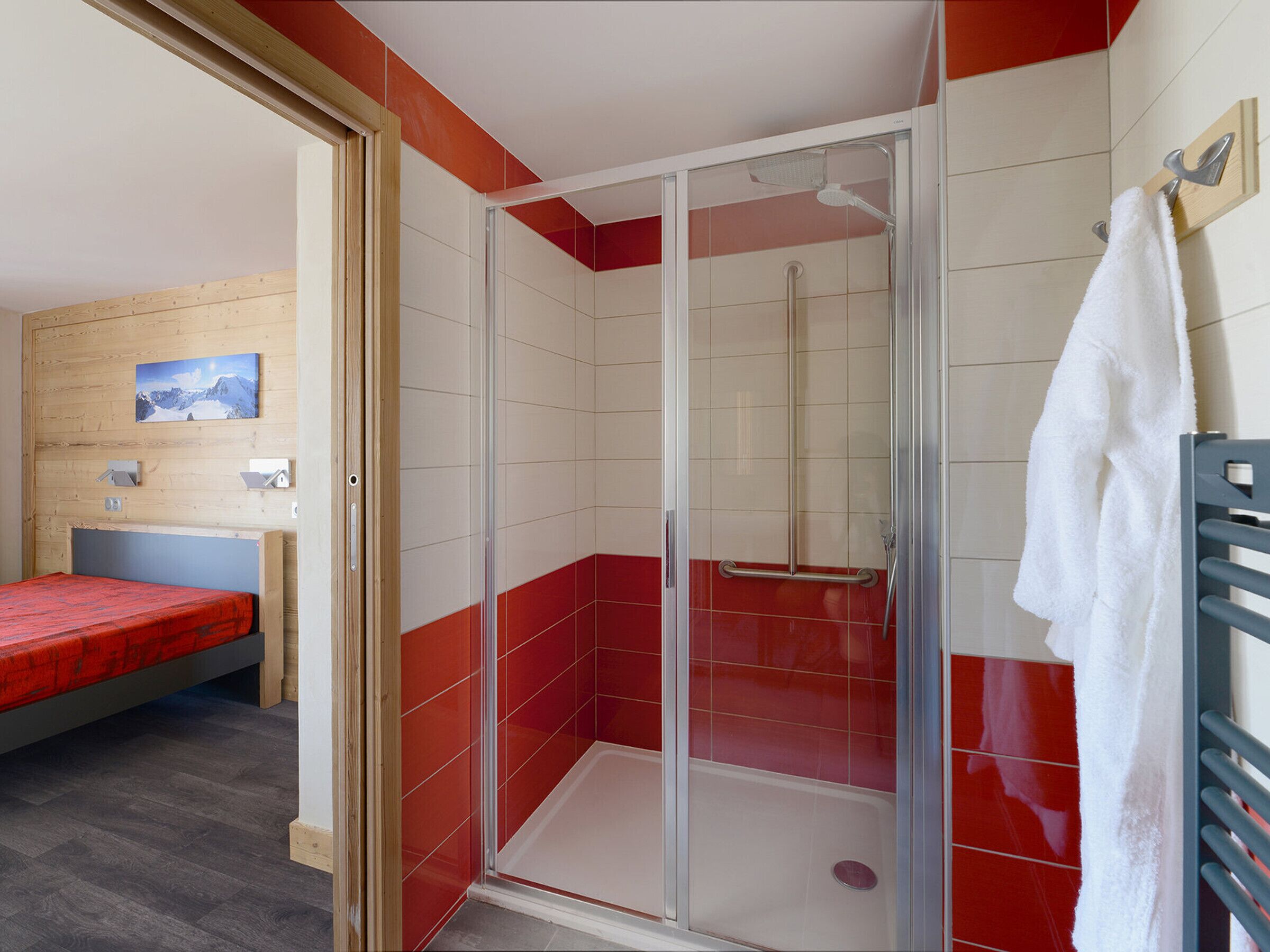 A room with a shower, a bed, and a towel rack.
