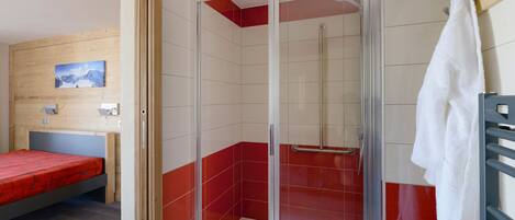 A room with a shower, a bed, and a towel rack.