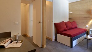 A compact bedroom with a bed, a small table, and a magazine on a table.