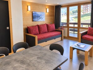 A modern room with a wooden sofa, a dining table, and chairs.