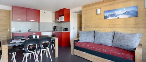 A compact living space with a kitchenette, dining area, and a sofa.