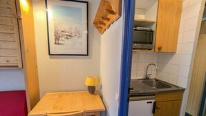 A compact kitchen with a wooden table, a sink, and a small refrigerator.