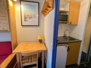 Uma cozinha compacta com uma mesa de madeira, pia e um refrigerador pequeno.
