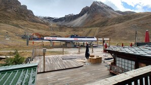 A mountain lodge with a wooden deck, a ski lift, and a sign reading "Bollin Fresse".