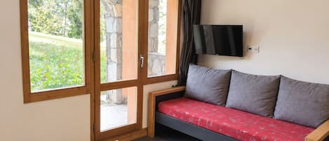 Una habitación con sofá, televisor en la pared y una mesa con control remoto.