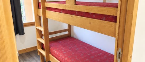 A bunk bed with a red mattress and wooden frame.