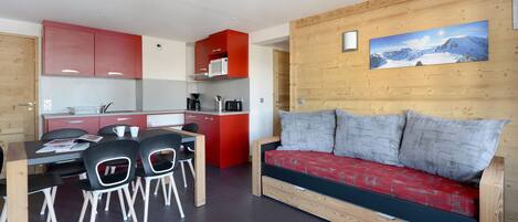 Un espacio habitable compacto con kitchenette, comedor y sofá.