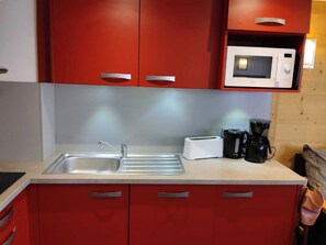 Cozinha com pia dupla, torradeira, cafeteira e micro-ondas.