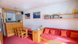 A compact living space with a kitchenette, a dining area, and a red sofa.