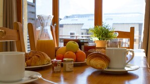 A breakfast table with croissants, fruit, honey, and a coffee cup. - Ski-in studio with WiFi and pets allowed (Briançon)