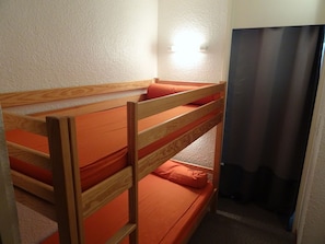 A bunk bed with orange bedding in a room with white walls and a door. - PMR Studio near slopes with mountain nook and balcony (La Salle-les-Alpes)