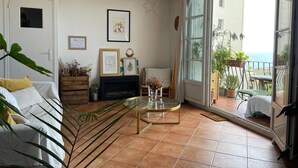 A living room with a glass coffee table, a sofa, and a view of the sea through a sliding glass door. - Sea view apartment with terrace, 3bedroom, 200m from Mourillon beaches (Toulon)
