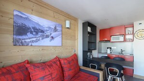 A modern living room with a wooden wall, a red sofa, and a large mountain landscape painting.