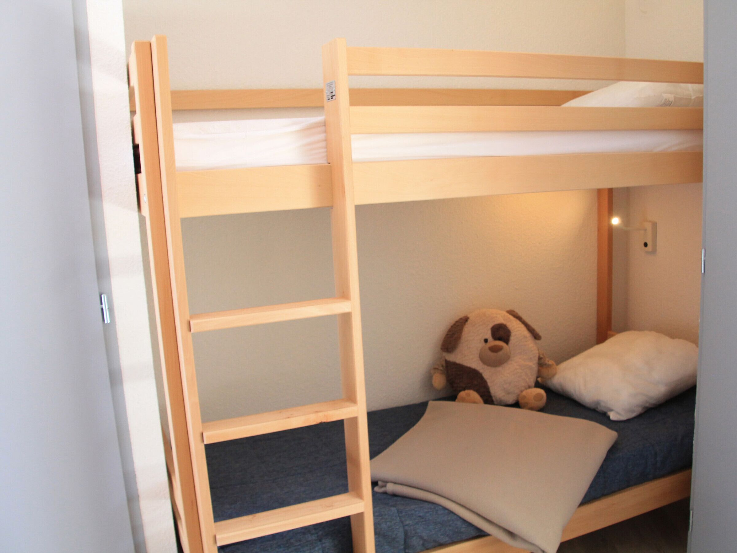A bunk bed with a ladder, a stuffed dog toy, and a pillow.