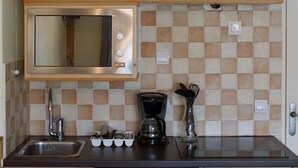 A kitchen with wooden cabinets, a stainless steel microwave, a coffee maker, and a sink. - Bright renovated studio at the foot of the slopes - Free wifi - Pets allowed (Briançon)