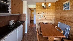 A kitchen with a wooden table and chairs, a microwave, and a kettle.
