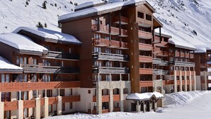 A multi-story hotel with balconies, stone facade, and snow-covered surroundings.