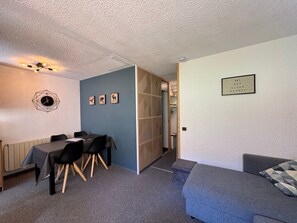A room with a dining table, chairs, a sofa, a wall clock, and a framed quote.