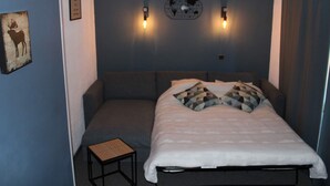 A bedroom with a bed, two wall-mounted lights, a small table, and a world map decoration. - Renovated Studio 2019 · Ski-in Ski-out · Balcony (Belle Plagne)