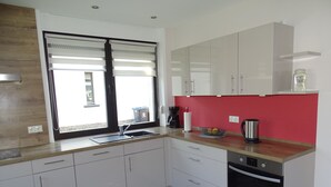 A modern kitchen with white cabinets, a wooden countertop, a stainless steel sink, a coffee maker, and a kettle. - Vacation home with garden and terrace, 15 minutes from the Moselle (Blankenrath)