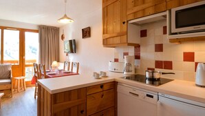 Una cocina con armarios de madera, microondas, cafetera y lavavajillas.