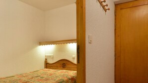 Un dormitorio con una cama de madera, una puerta y un perchero en la pared.