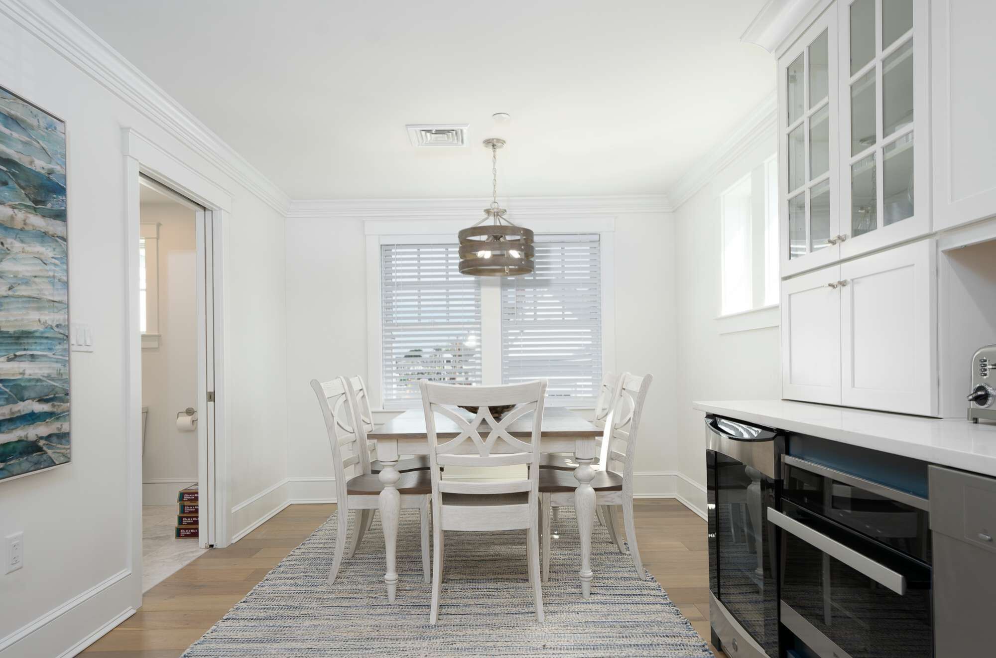 A modern kitchen with white cabinetry, a built-in oven, and a hanging pendant light.