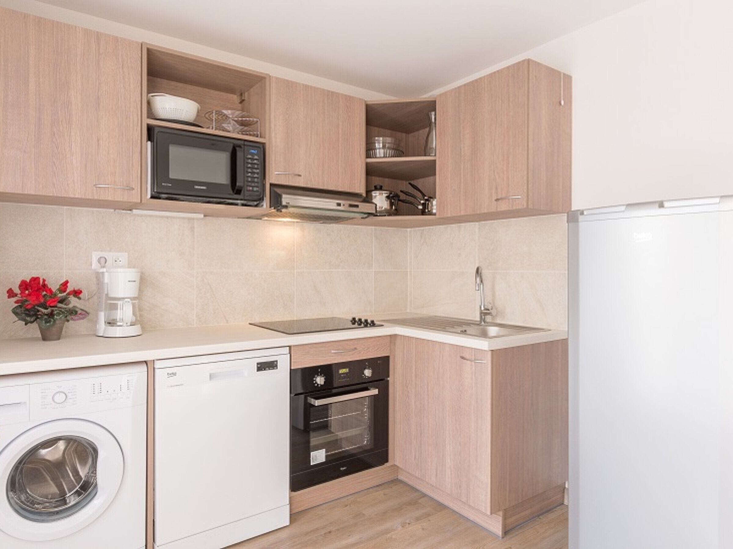 A compact kitchen with a microwave, oven, dishwasher, and sink.