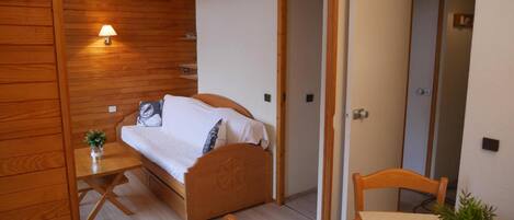 A bedroom with a bed, bedside table, lamp, and a small plant.