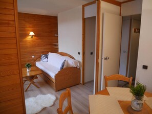 A bedroom with a bed, bedside table, lamp, and a small plant.